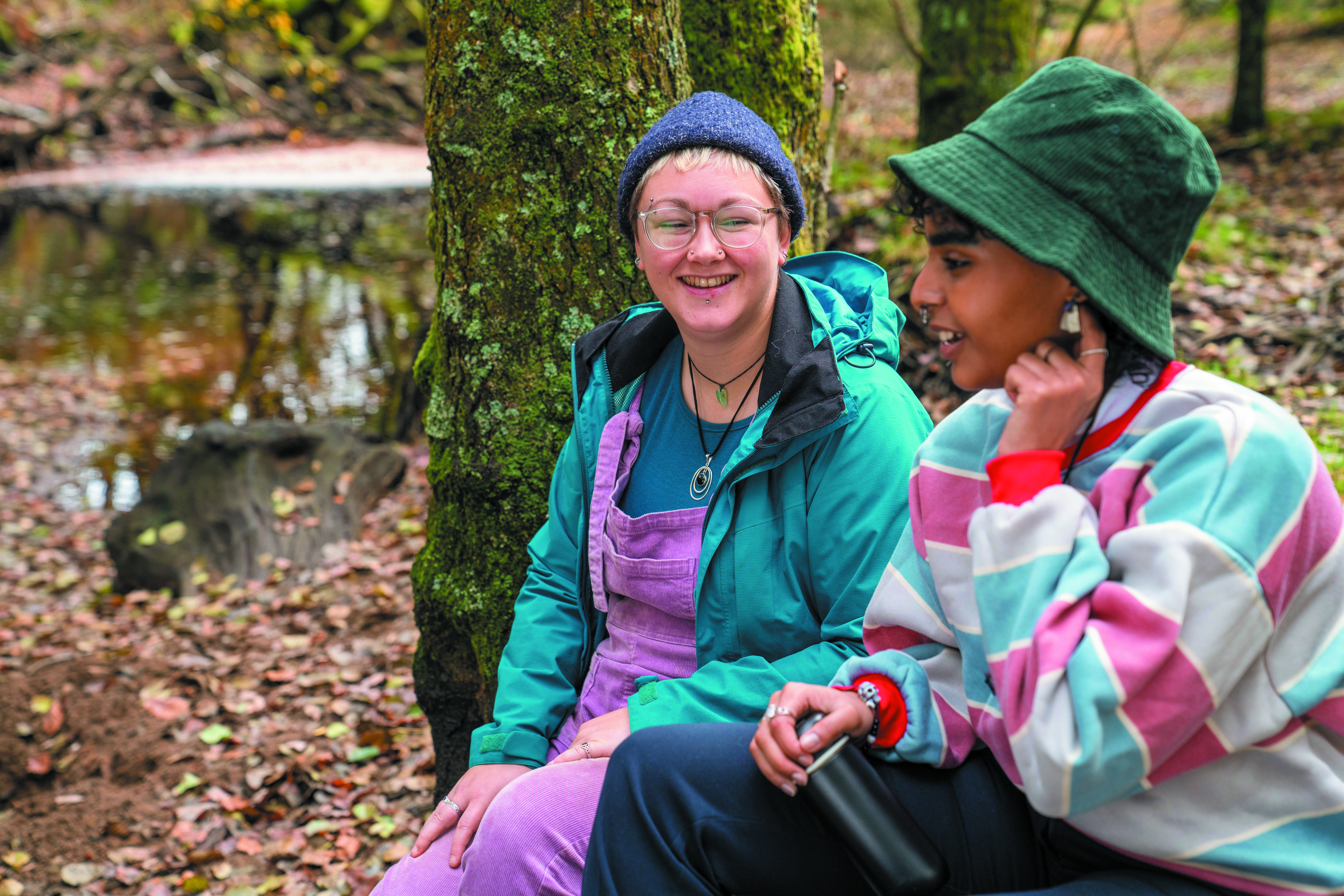 Smiling female friends sitting in forest